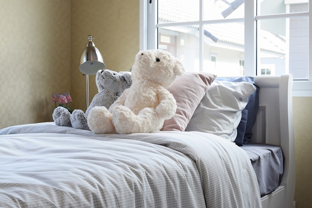 Kids room with dolls and pillows on bed and bedside table lamp