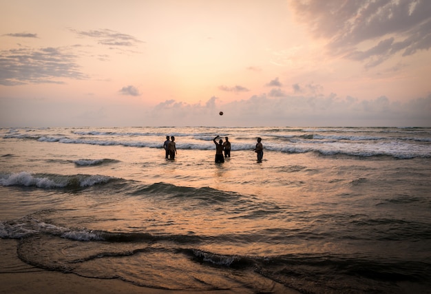 Kids silhouettes having happy time on sea beach near sunset