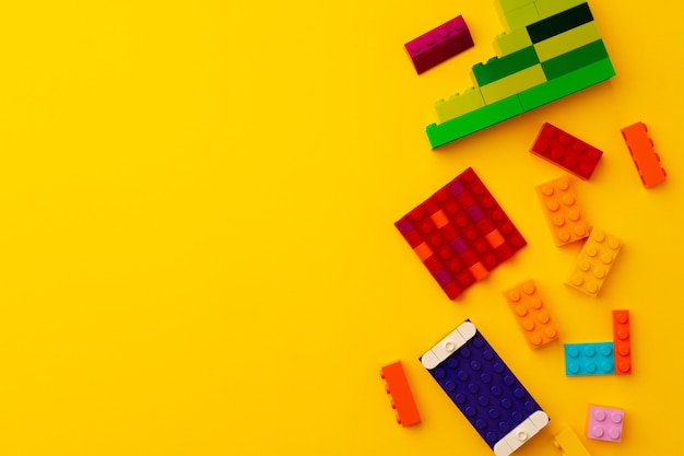 Kids toy constructor details scattered on yellow background