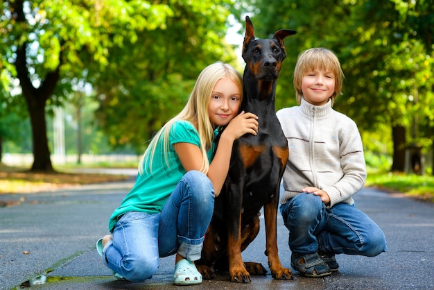 Kids with dobermann in summer park.