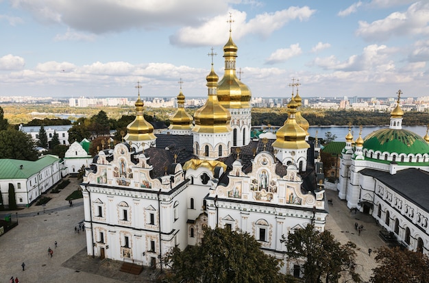 Kiev Pechersk Lavra. Cathedral of the Dormition. Kiev. Ukraine. Green and yellow autumn trees on background. Dnieper River and the panorama of Kiev in the background