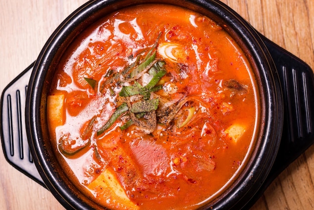 Kimchi soup in hot black iron pot Korean traditional Kimchi Jjigae soup in bowl in the restaurant