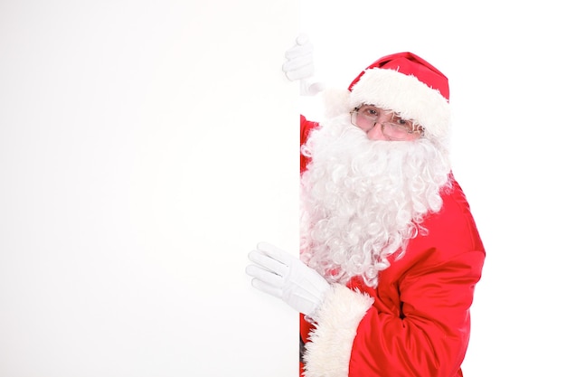 Kind Santa Claus pointing in white blank sign, isolated on white background.