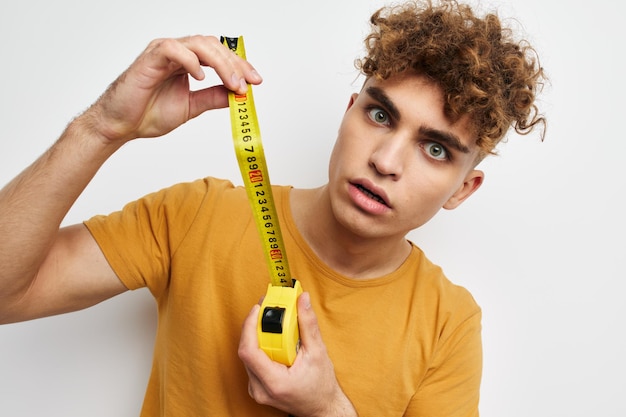 Kinky guy measuring tape measure in yellow tshirt light background