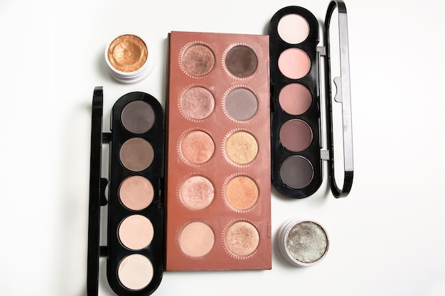 Kit of professional makeup palettes in nude color with cream eyeshadows over a white background