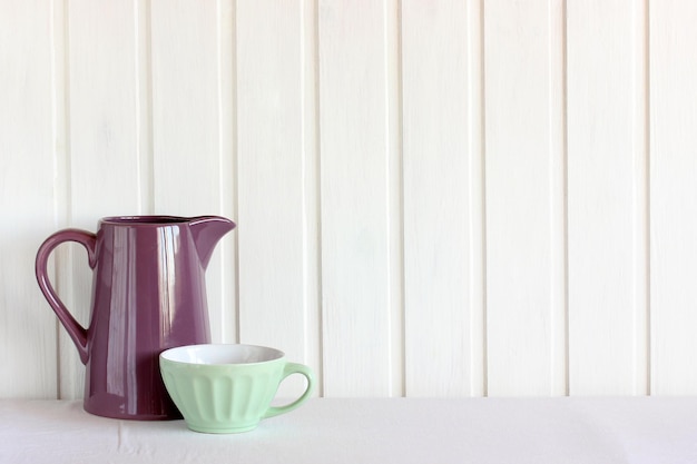 Kitchen background with jug and bowl A shelf with dishes against a white wooden wall