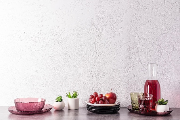 Kitchen background with modern utensils jug with grape juice a branch of grapes on a plate still life front view a copy space