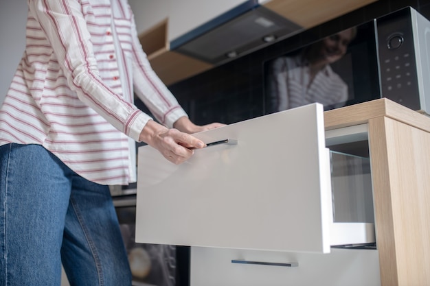 Photo in the kitchen. close up picture of a woman opening the drawer