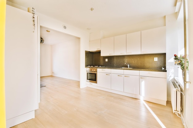 a kitchen and dining area in an apartment with white cabinets wood flooring and yellow door leading to the living room