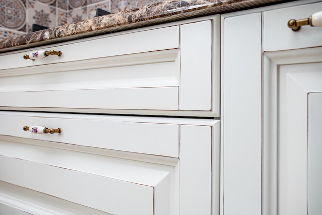 Kitchen doors and drawers of white kitchen in country style design with granite countertop closeup