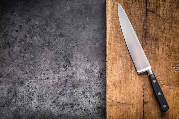 Kitchen knife on concrete or wooden board.