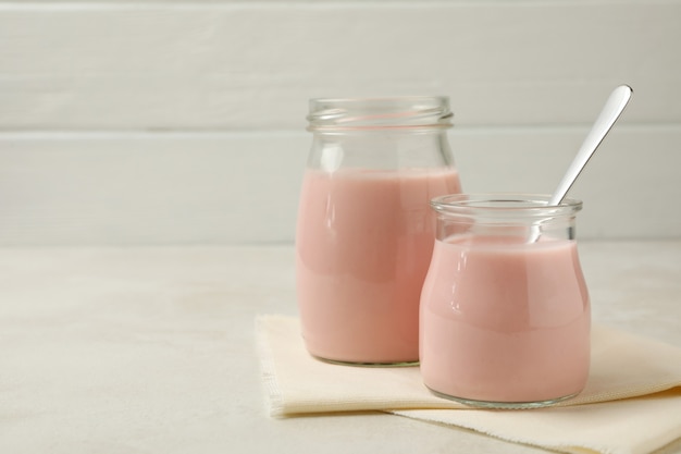 Kitchen napkin with jars of yogurt on white textured background