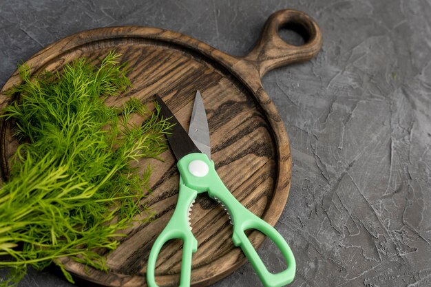 Kitchen scissors cutting dill in the kitchen on a cutting board