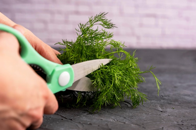 Kitchen scissors cutting dill in the kitchen on a cutting board