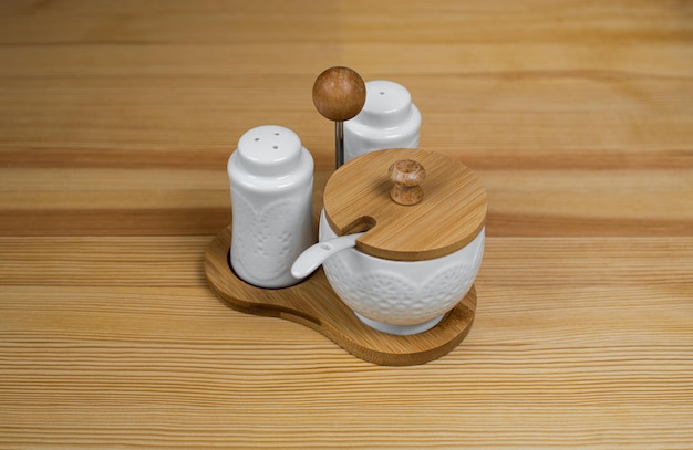 A kitchen set that includes sugar pepper and salt with a spoon