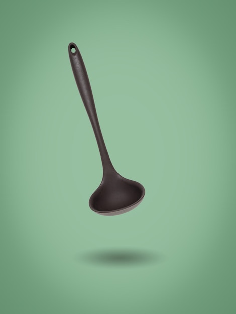 Kitchen silicone ladle on a green background