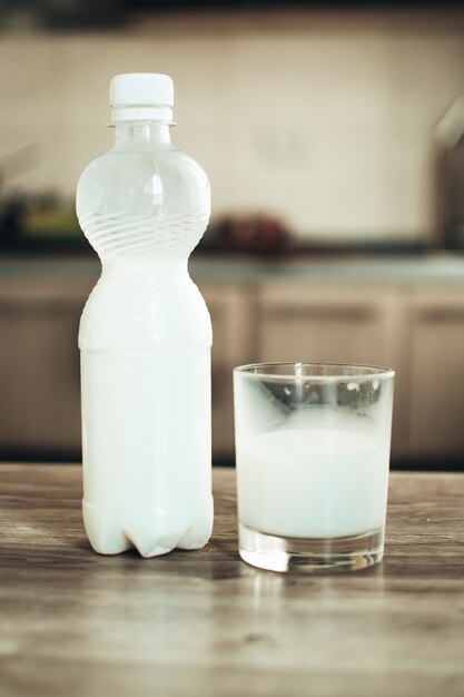 On the kitchen table stands a bottle of milk next to a glass of milk too