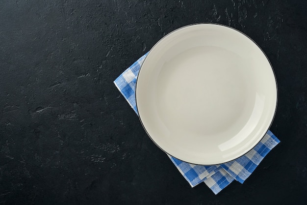 Kitchen table with empty plate white color, blue tablecloth and space for your recipe or menu.