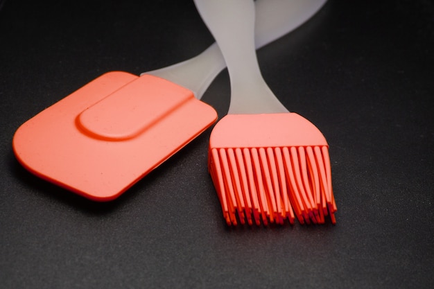 Kitchen tools on a black background. Silicone spatula, brush close up