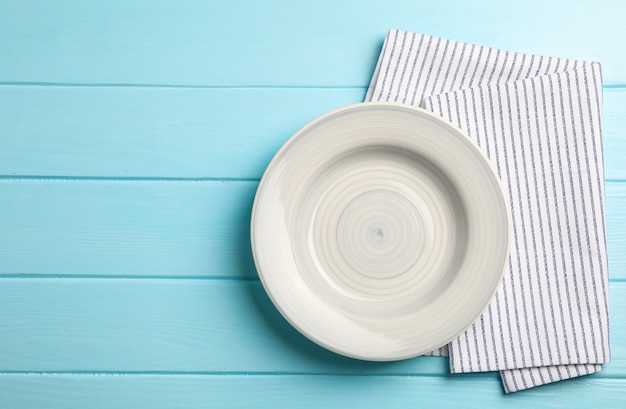 Kitchen towel with plate on wooden background, top view