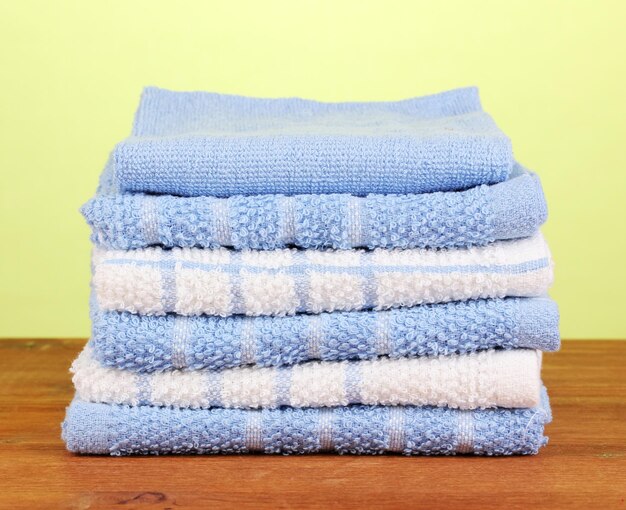 Kitchen towels on wooden table on green background closeup