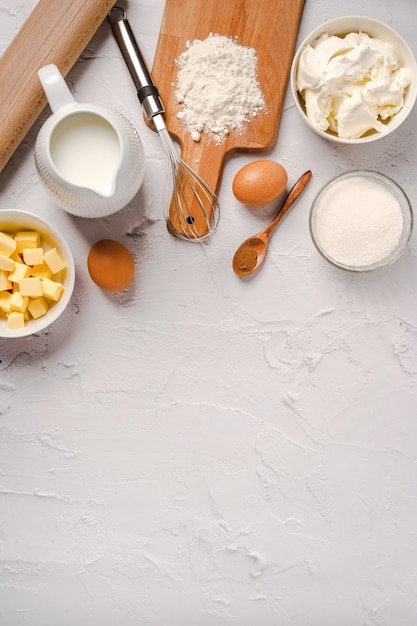 Kitchen utensils and baking ingredients for cupcakes on white stone background