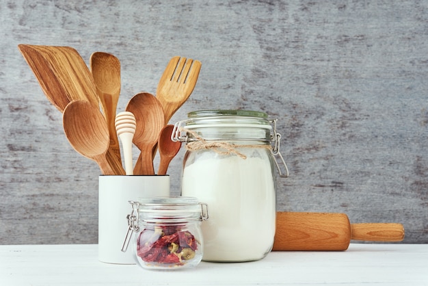 Kitchen utensils with wooden cutlery and rolling pin on a white table