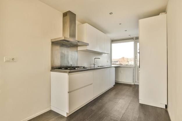 A kitchen with white cabinetry and a large window