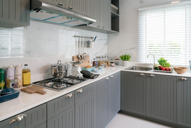 Kitchen wood utensils, chef accessories. Hanging copper kitchen with white tiles wall.