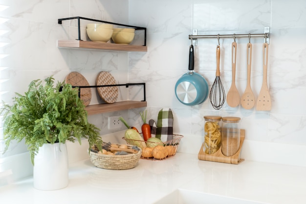 Kitchen wood utensils, chef accessories. Hanging copper kitchen with white tiles wall.