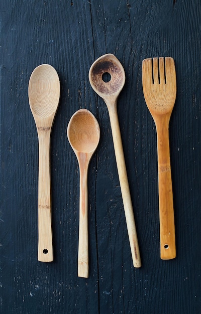 Kitchen wooden utensils over black wooden table above view