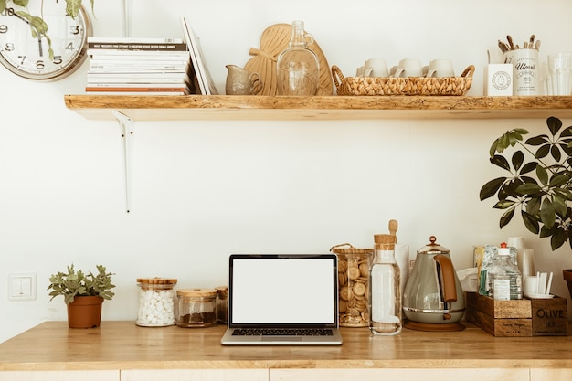 Kitchen workspace with blank copy space mock up laptop screen. Modern stylish kitchen interior design with wooden kitchenware.