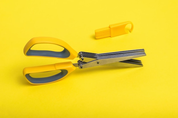 Kitchen yellow salad clippers with a cleaning device on a bright yellow background Devices for slicing salad