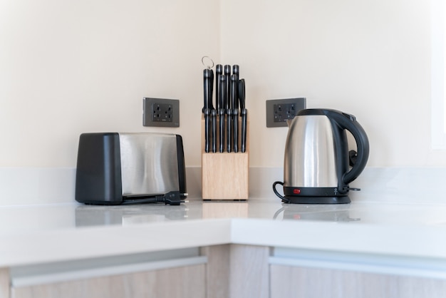 Kitchenette consist of toaster, kettle and a set of knives on kitchen counter