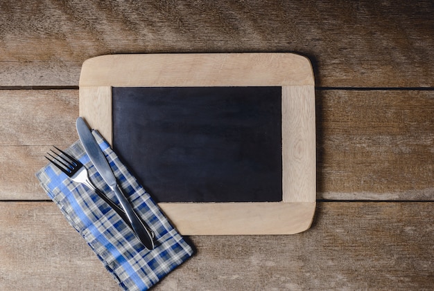 Kitchenware on a blackboard with a blue checkered napkin