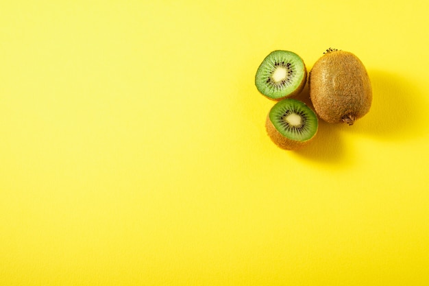 Kiwi fruits half sliced on vibrant plain yellow