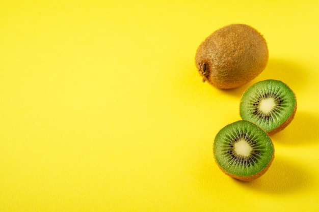 Kiwi fruits half sliced on vibrant plain yellow