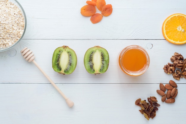 Kiwi, honey and dried apricots lie on a white wooden table. Healthy breakfast.