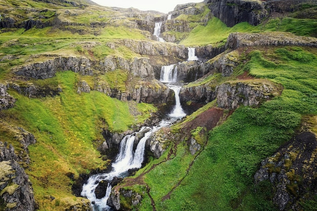 Klifbrekkufossar seven tier waterfall flowing hidden in the Mjoifjordur Fjord on summer at Iceland