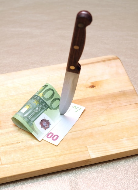 A knife cutting a 100 euro note into a knife.