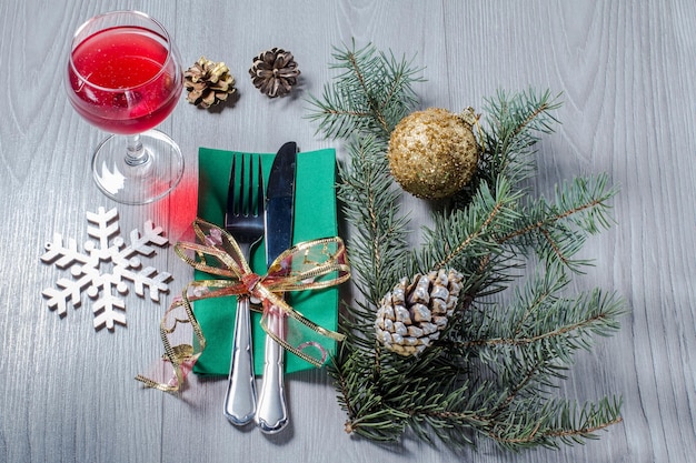 Knife and fork on green napkin with glass of wine in New Year's scenery