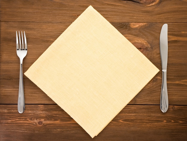 Knife and fork at napkin on wooden 