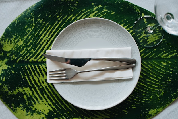 Knife and fork placed on a napkin on a white plate. Placed on a sheet for a wedding