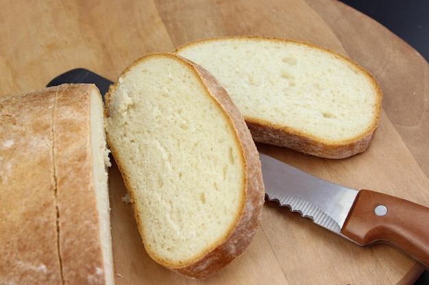 Knife is cutting a loaf of bread into slices Cut fresh bread with a knife