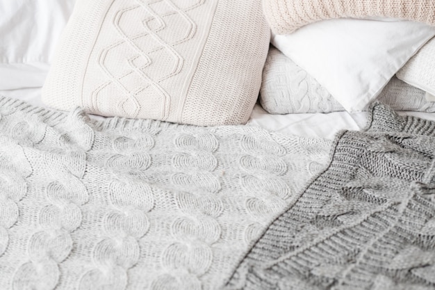 Knitted bedding style. Bedroom coziness. Pillows and blankets background.