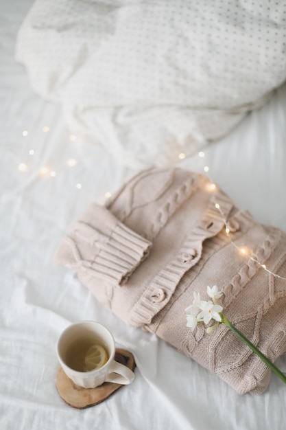 Knitted beige sweater and delicate spring flower Winter and spring fashion concept