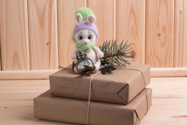 Knitted bunny with gifts on a wooden background with a Christmas tree New Year of the hare 2023 handmade