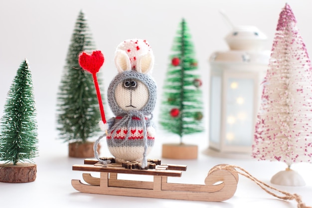 Knitted bunny with gifts on a wooden background with a Christmas tree New Year of the hare 2023 handmade