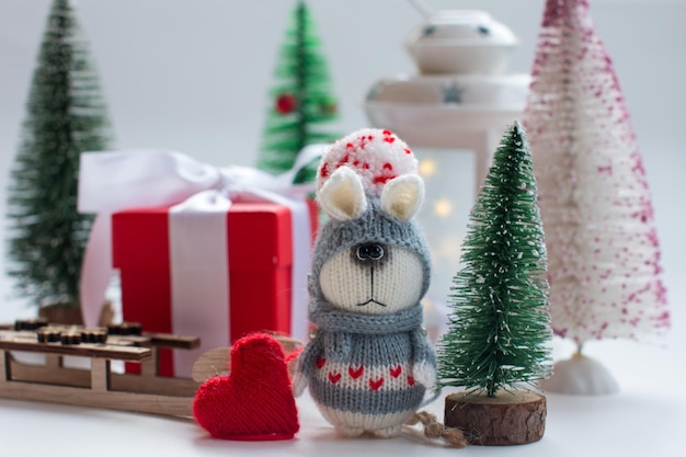 Knitted bunny with gifts on a wooden background with a Christmas tree New Year of the hare 2023 handmade