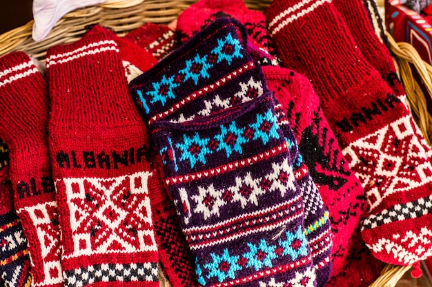 Knitted clothes. Knitted gloves and socks with colorful ornaments for sale on the market in Kruje